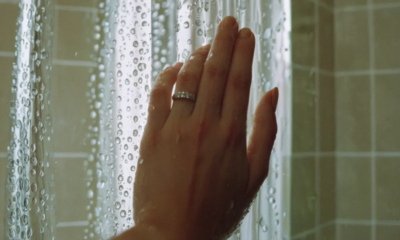 A close-up shot capturing a hand reaching from inside a shower, holding a shower curtain and questioning its placement, exemplifying the debate of whether shower curtains go inside or outside.