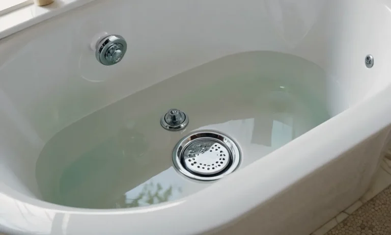 A close-up photo showcasing a shiny tub drain and overflow kit, flawlessly installed in a pristine bathtub, highlighting its high-quality construction and functionality.