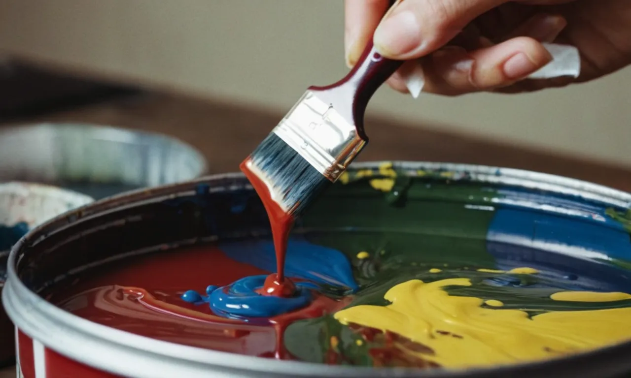 A close-up image capturing a hand gently cleaning an artist's paintbrush, immersed in a container of the best brush cleaner for acrylic paint, showcasing the removal of vibrant paint pigments.