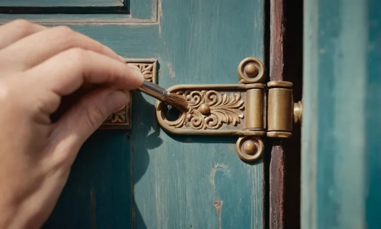 A close-up photo captures a hand holding a small brush, delicately cleaning the intricate details of a door hinge, showcasing the meticulous process of maintaining cleanliness without removing the hinges.
