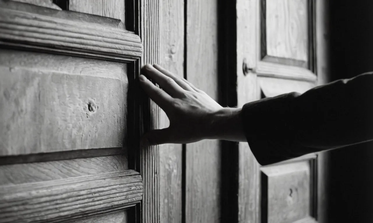 A black and white image capturing a person, their hand gently extended, as they hold open a weathered wooden door for an unseen figure, symbolizing kindness, courtesy, and the beauty of simple gestures.