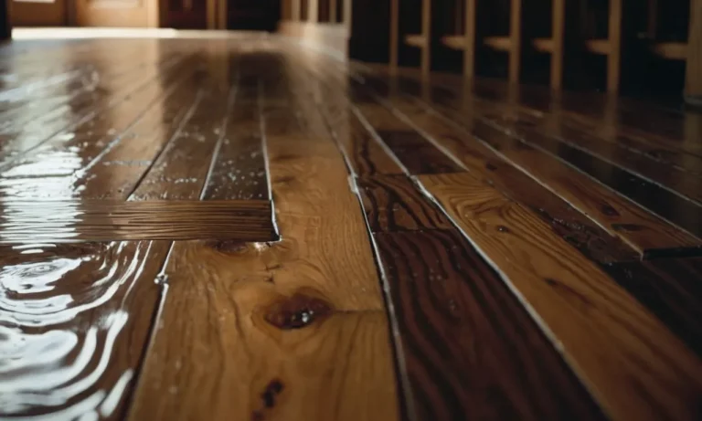 A close-up photo captures a warped wooden floor with visible stains and discoloration, revealing telltale signs of water damage as it seeps through the surface, hinting at potential underlying issues.