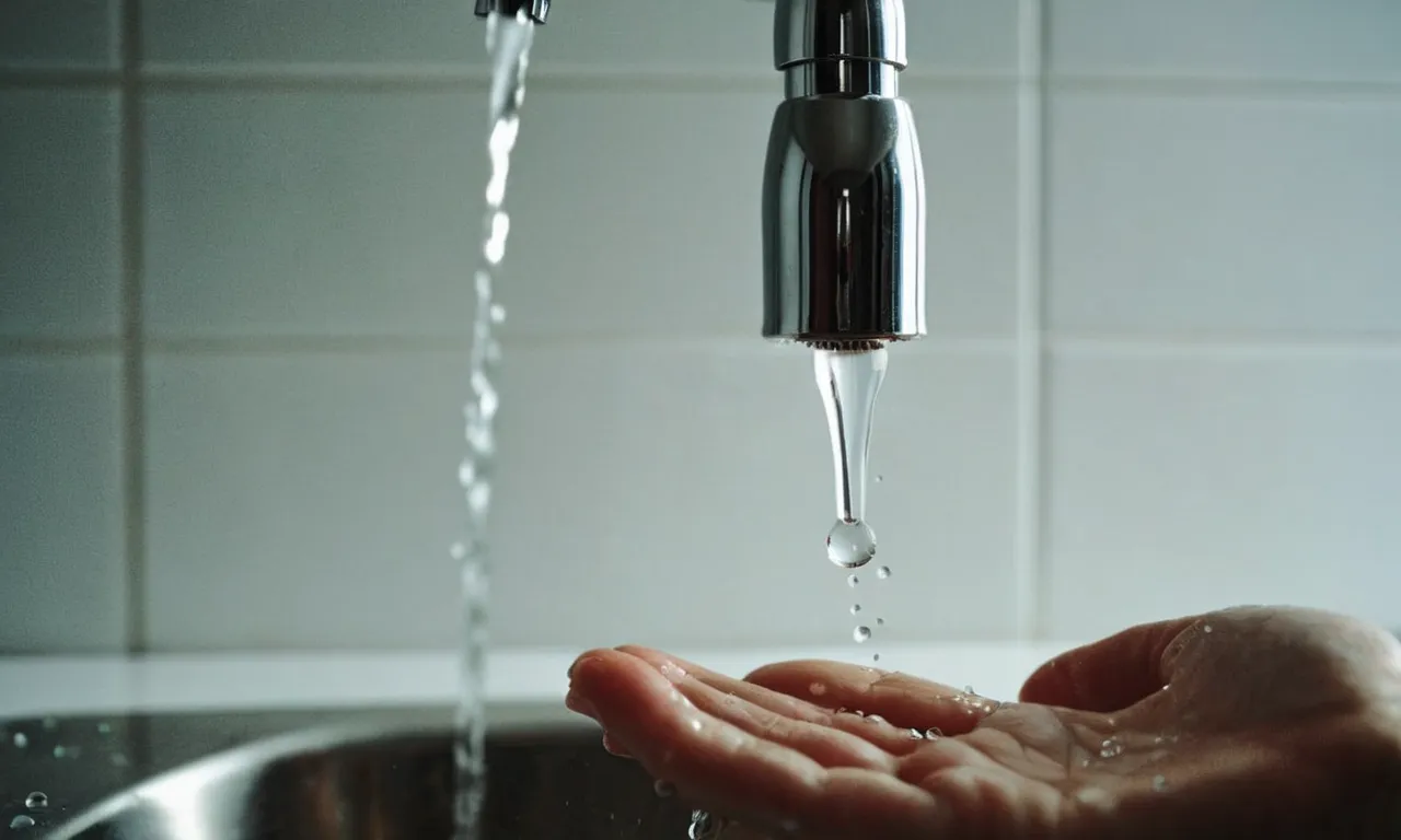 A close-up shot capturing the frustration of a person's hand under a running faucet, with droplets suspended in mid-air, symbolizing the absence of water flowing from the tap.